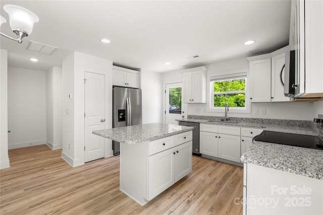 210 N Correll St, Landis, NC 28025 - kitchen with appliances with stainless steel finishes, a sink, a center island, white cabinets, and light wood finished floors