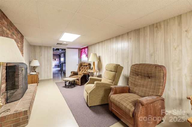 765 York Institute Rd, Hiddenite, NC 28636 - sitting room with wood walls, a brick fireplace, finished concrete floors, and a drop ceiling