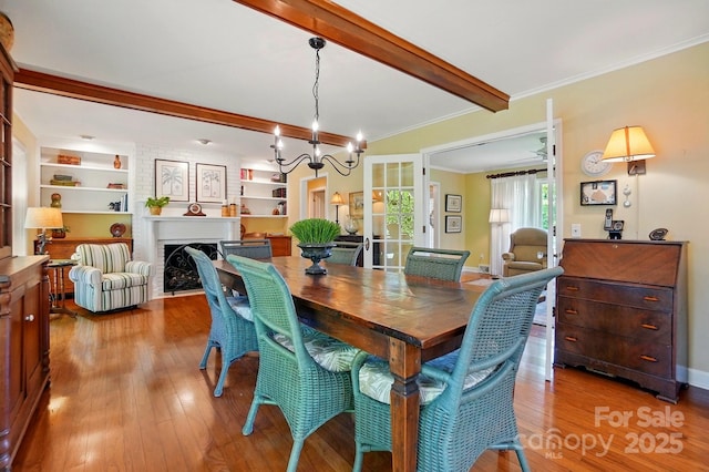 308 Odell St, Kannapolis, NC 28083 - dining area with beamed ceiling, a chandelier, wood finished floors, a fireplace, and crown molding