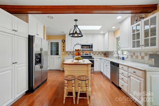308 Odell St, Kannapolis, NC 28083 - kitchen with appliances with stainless steel finishes, a skylight, a center island, white cabinets, and a sink