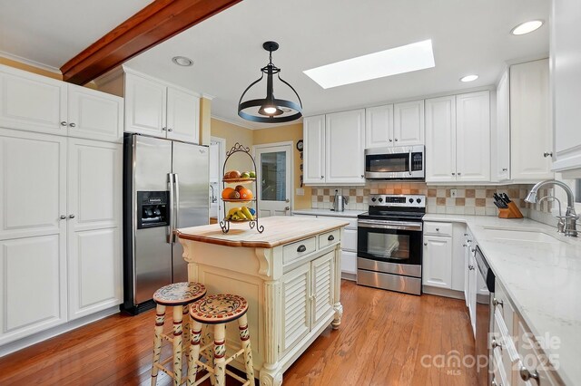 308 Odell St, Kannapolis, NC 28083 - kitchen with appliances with stainless steel finishes, a sink, a skylight, recessed lighting, and decorative backsplash