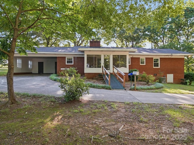 2216 Griffith Rd, Monroe, NC 28112 - ranch-style house featuring brick siding, a chimney, concrete driveway, a carport, and a sunroom