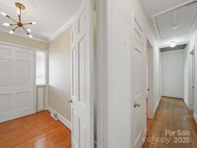 2216 Griffith Rd, Monroe, NC 28112 - hallway with attic access, light wood-type flooring, a chandelier, baseboards, and crown molding