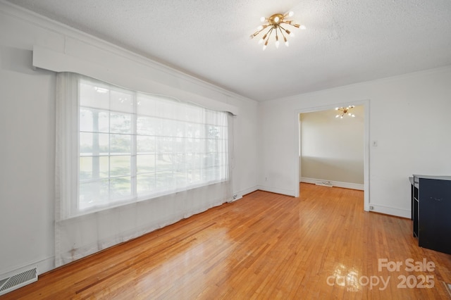 2216 Griffith Rd, Monroe, NC 28112 - spare room with a chandelier, light wood-style flooring, a textured ceiling, and ornamental molding