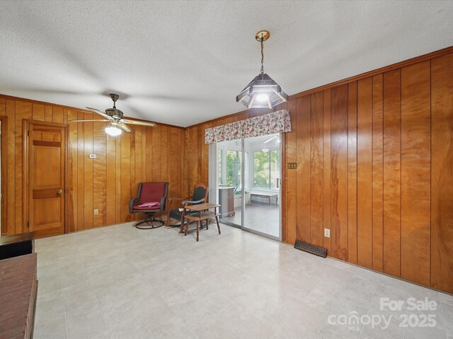 2216 Griffith Rd, Monroe, NC 28112 - living area featuring wood walls, a ceiling fan, and a textured ceiling