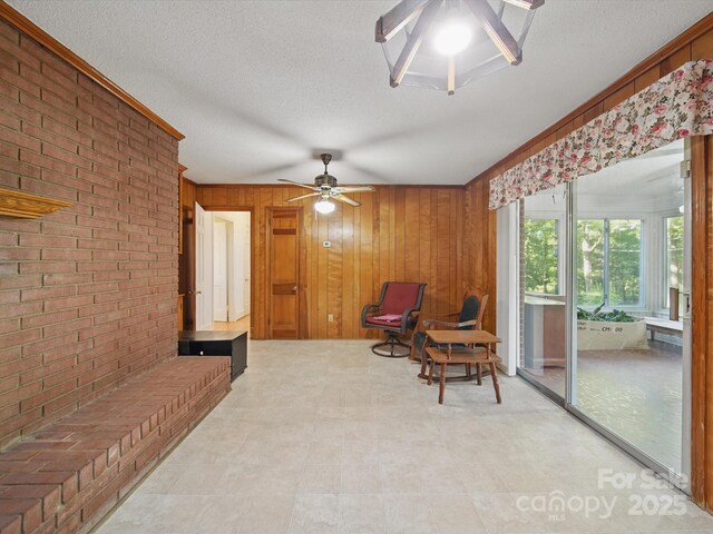 2216 Griffith Rd, Monroe, NC 28112 - sitting room featuring a ceiling fan, wood walls, brick wall, a textured ceiling, and tile patterned floors