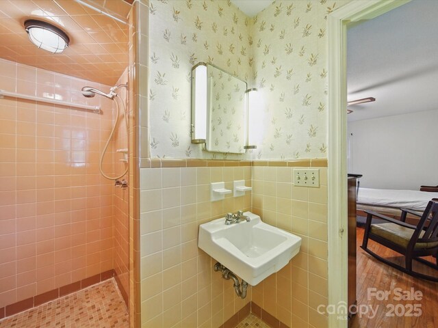 2216 Griffith Rd, Monroe, NC 28112 - full bath featuring tiled shower, wainscoting, wallpapered walls, wood finished floors, and a sink