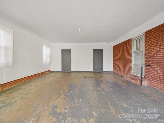 2216 Griffith Rd, Monroe, NC 28112 - spare room with brick wall and concrete floors