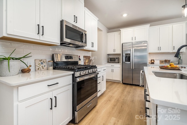 16018 River Tree Ln, Charlotte, NC 28278 - kitchen featuring appliances with stainless steel finishes, a sink, white cabinetry, light wood-style floors, and tasteful backsplash