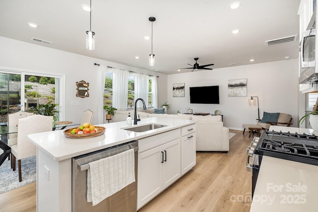 16018 River Tree Ln, Charlotte, NC 28278 - kitchen featuring appliances with stainless steel finishes, a sink, open floor plan, light wood-style flooring, and white cabinetry