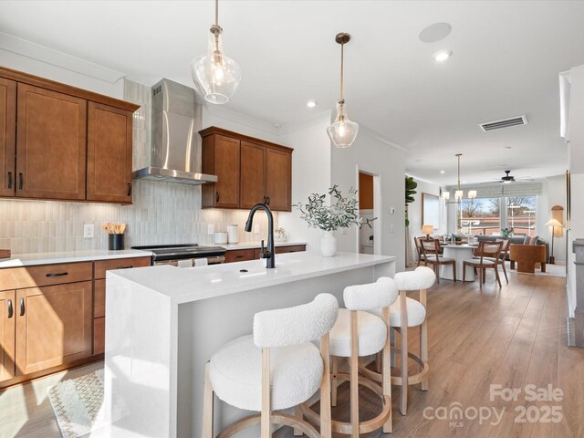 5508 Swaling St, Charlotte, NC 28217 - kitchen featuring wall chimney range hood, light countertops, tasteful backsplash, light wood-style floors, and recessed lighting