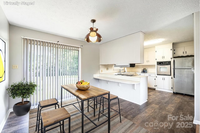 1515 Fairway Acres Rd, Lenoir, NC 28645 - kitchen featuring appliances with stainless steel finishes, a peninsula, light countertops, a textured ceiling, and dark wood finished floors