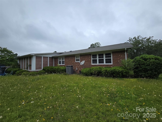 116 E Graves St, Candor, NC 27229 - rear view of house featuring a sunroom, central AC unit, brick siding, and a lawn