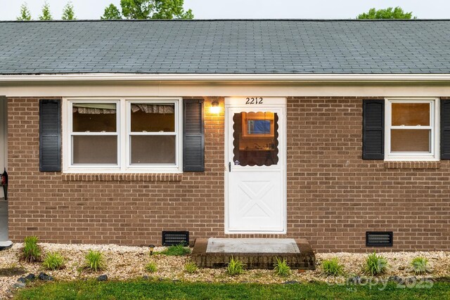view of exterior entry featuring crawl space and brick siding