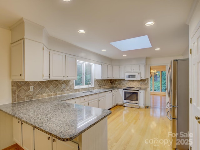 8 Sunrise Point Rd, Lake Wylie, SC 29710 - kitchen with appliances with stainless steel finishes, a sink, a peninsula, a skylight, and light wood-style flooring