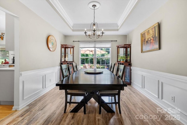16018 Hollingbourne Rd, Huntersville, NC 28078 - dining area with a chandelier, a tray ceiling, a decorative wall, crown molding, and light wood-type flooring