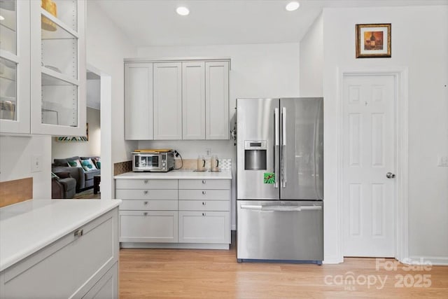 16018 Hollingbourne Rd, Huntersville, NC 28078 - kitchen with stainless steel refrigerator with ice dispenser, light countertops, light wood-style floors, recessed lighting, and glass insert cabinets