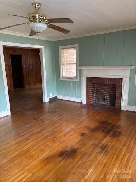 8000 Chapman St, Charlotte, NC 28216 - unfurnished living room featuring ceiling fan, crown molding, a brick fireplace, wood finished floors, and baseboards
