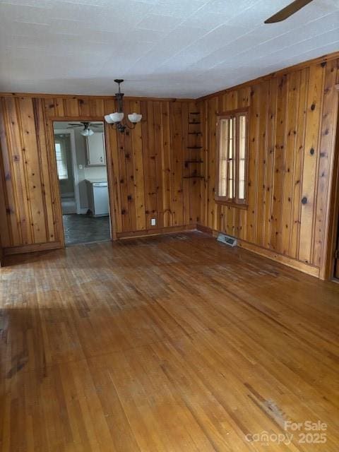 8000 Chapman St, Charlotte, NC 28216 - spare room with ceiling fan, hardwood / wood-style flooring, wood walls, a chandelier, and baseboards