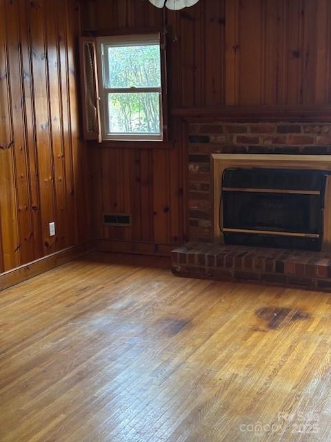 8000 Chapman St, Charlotte, NC 28216 - unfurnished living room featuring wood finished floors, a fireplace, and wooden walls