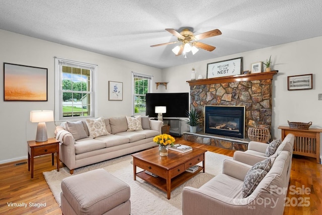 139 Pleasant Garden Dr, Taylorsville, NC 28681 - living area with wood finished floors, ceiling fan, a fireplace, a textured ceiling, and baseboards