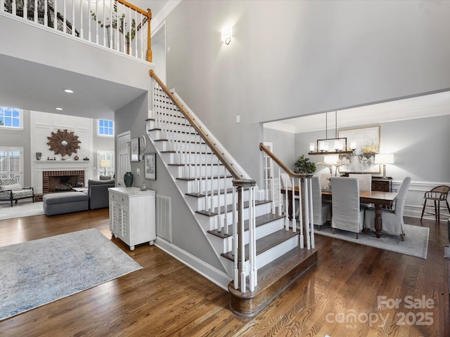 16308 Woolwine Rd, Charlotte, NC 28278 - stairs with a towering ceiling, wood finished floors, a brick fireplace, crown molding, and baseboards