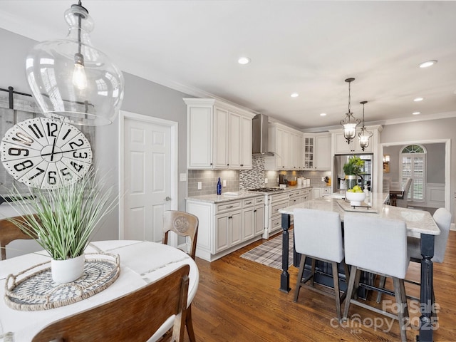 16308 Woolwine Rd, Charlotte, NC 28278 - kitchen featuring wall chimney exhaust hood, crown molding, glass insert cabinets, a breakfast bar, and light wood finished floors