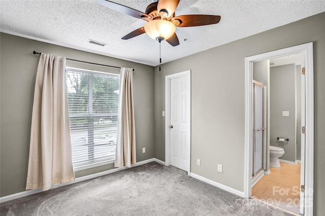 753 SW Dr, Davidson, NC 28036 - unfurnished bedroom featuring a textured ceiling, baseboards, ensuite bathroom, ceiling fan, and carpet floors