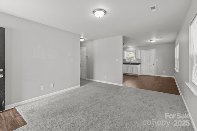252 Sweet Bay Ln NW, Concord, NC 28027 - unfurnished living room featuring dark colored carpet, baseboards, and a sink