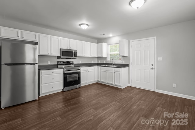 252 Sweet Bay Ln NW, Concord, NC 28027 - kitchen with appliances with stainless steel finishes, a sink, dark countertops, dark wood-style flooring, and white cabinets
