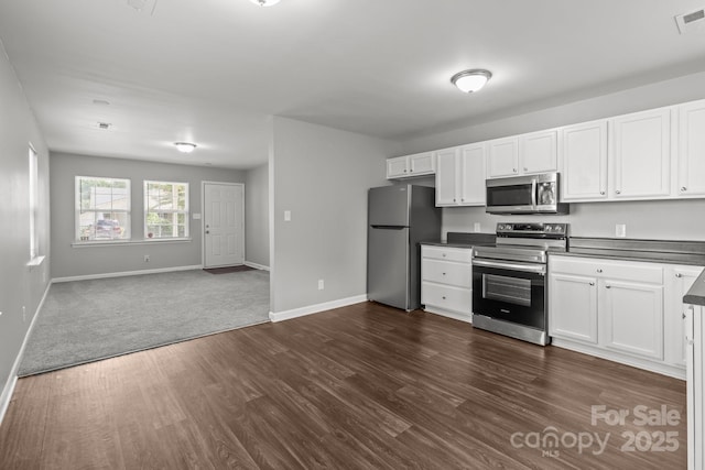 252 Sweet Bay Ln NW, Concord, NC 28027 - kitchen with appliances with stainless steel finishes, dark countertops, dark wood-style flooring, open floor plan, and white cabinets