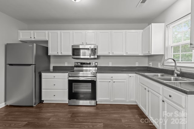 252 Sweet Bay Ln NW, Concord, NC 28027 - kitchen with stainless steel appliances, a sink, white cabinets, dark countertops, and dark wood-style flooring