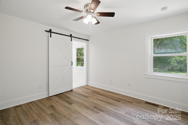 615 Irish Potato Rd, Concord, NC 28025 - unfurnished bedroom with multiple windows, wood finished floors, a barn door, and baseboards