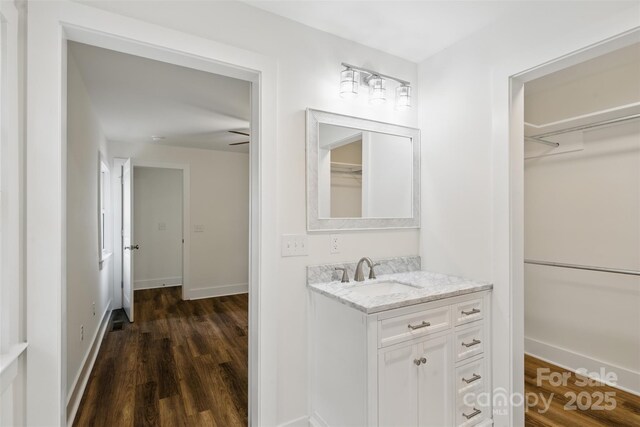 615 Irish Potato Rd, Concord, NC 28025 - bathroom featuring vanity, wood finished floors, a walk in closet, and baseboards