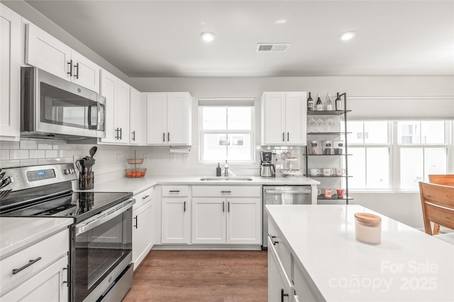 5023 Daybell St, Charlotte, NC 28214 - kitchen featuring appliances with stainless steel finishes, a sink, light countertops, backsplash, and white cabinets