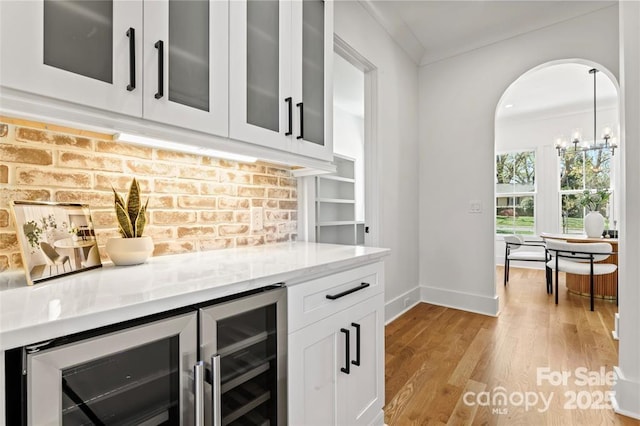 621 Poindexter Dr, Charlotte, NC 28209 - indoor dry bar with baseboards, light wood-style floors, beverage cooler, crown molding, and arched walkways