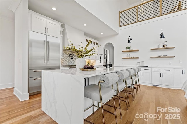 621 Poindexter Dr, Charlotte, NC 28209 - kitchen with stainless steel built in fridge, arched walkways, open shelves, a sink, and light wood-style flooring