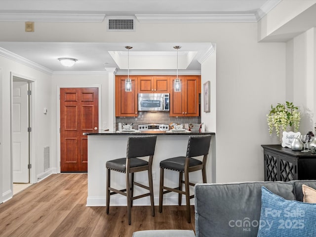 300 W 5th St Unit 433, Charlotte, NC 28202 - kitchen featuring stainless steel microwave, dark countertops, stove, crown molding, and light wood-style floors