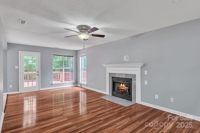 8120 Vermilion Dr, Charlotte, NC 28215 - unfurnished living room featuring wood finished floors, ceiling fan, a tile fireplace, baseboards, and a textured ceiling