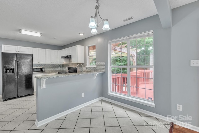 8120 Vermilion Dr, Charlotte, NC 28215 - kitchen with black appliances, under cabinet range hood, white cabinets, a peninsula, and a textured ceiling