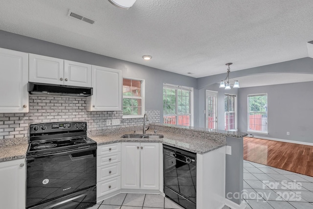 8120 Vermilion Dr, Charlotte, NC 28215 - kitchen with black appliances, a sink, under cabinet range hood, light tile patterned floors, and a chandelier