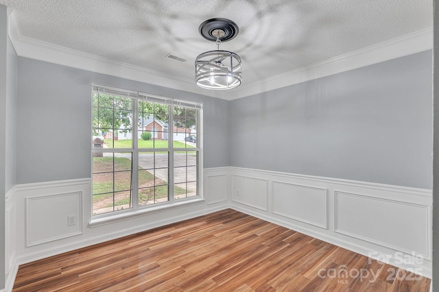 8120 Vermilion Dr, Charlotte, NC 28215 - empty room featuring wood finished floors, a textured ceiling, a chandelier, wainscoting, and ornamental molding