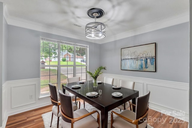 8120 Vermilion Dr, Charlotte, NC 28215 - dining space with wainscoting, crown molding, wood finished floors, and a decorative wall