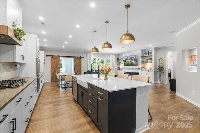 5050 Havencrest Dr, Fort Mill, SC 29715 - kitchen featuring a barn door, a sink, crown molding, stainless steel appliances, and wall chimney range hood