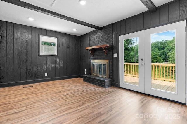 520 Hickory Ave, Hudson, NC 28638 - unfurnished living room with wood finished floors, french doors, beamed ceiling, wooden walls, and a brick fireplace