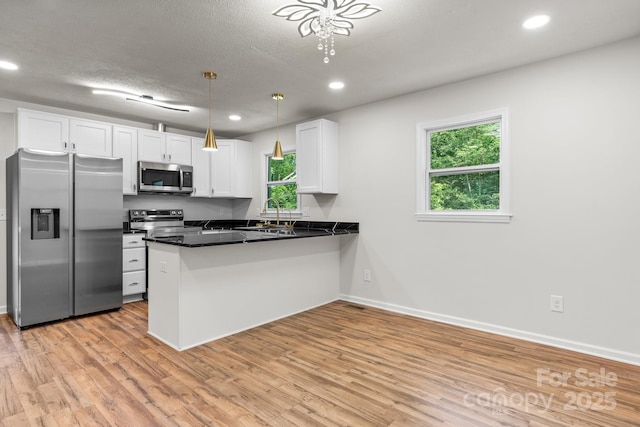 520 Hickory Ave, Hudson, NC 28638 - kitchen featuring appliances with stainless steel finishes, dark countertops, white cabinets, light wood-style floors, and a peninsula