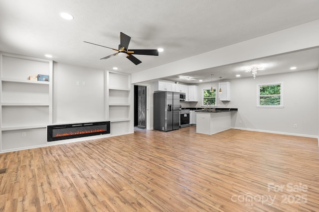 520 Hickory Ave, Hudson, NC 28638 - unfurnished living room with light wood finished floors, a glass covered fireplace, recessed lighting, ceiling fan, and built in features