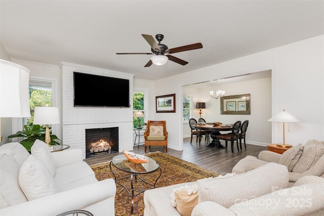 1041 Brawley School Rd, Mooresville, NC 28117 - living room with wood finished floors, ceiling fan, a brick fireplace, a chandelier, and baseboards