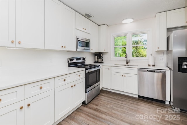 1041 Brawley School Rd, Mooresville, NC 28117 - kitchen featuring stainless steel appliances, a sink, light countertops, white cabinets, and light wood-style floors