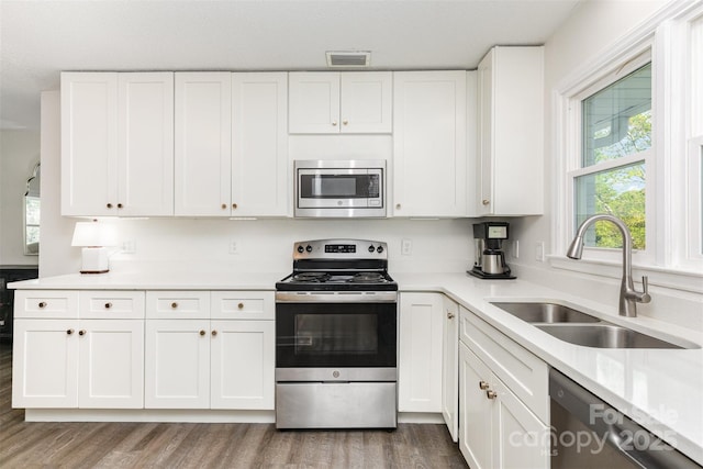 1041 Brawley School Rd, Mooresville, NC 28117 - kitchen featuring appliances with stainless steel finishes, a sink, white cabinetry, and wood finished floors